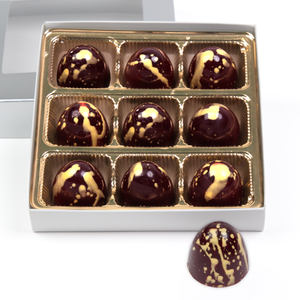 Twelve cherry coridal bonbons in gold and silver packaging and one out front